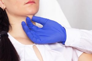 A person wearing a surgical glove examining a patient’s chin