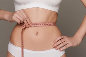 A person holding a measuring tape around her waist